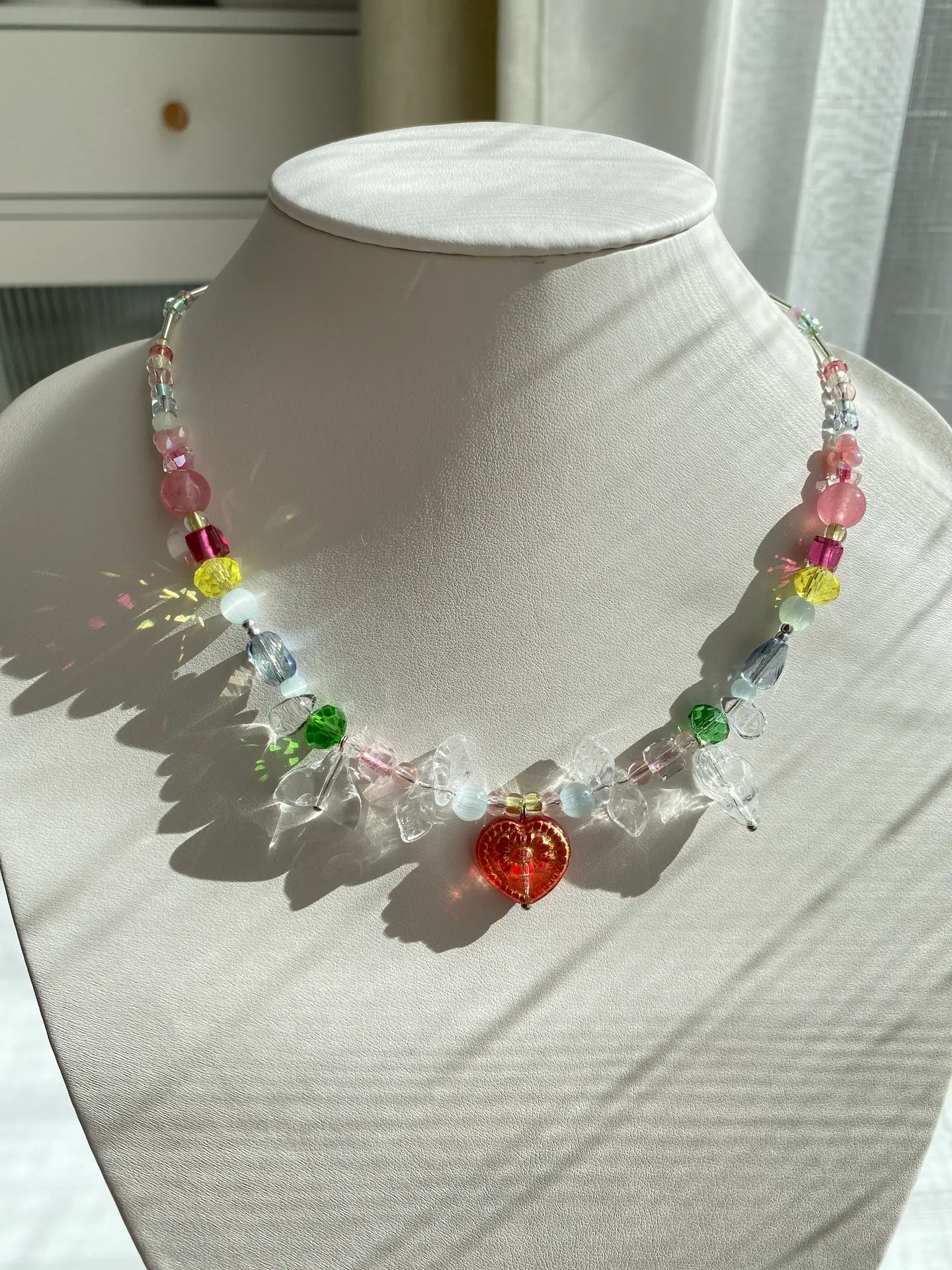 HuibenCraft vibrant multi-color seed bead necklace with a red gold-traced heart lampwork pendant and mermaid tail dangles, worn on a mannequin neck.