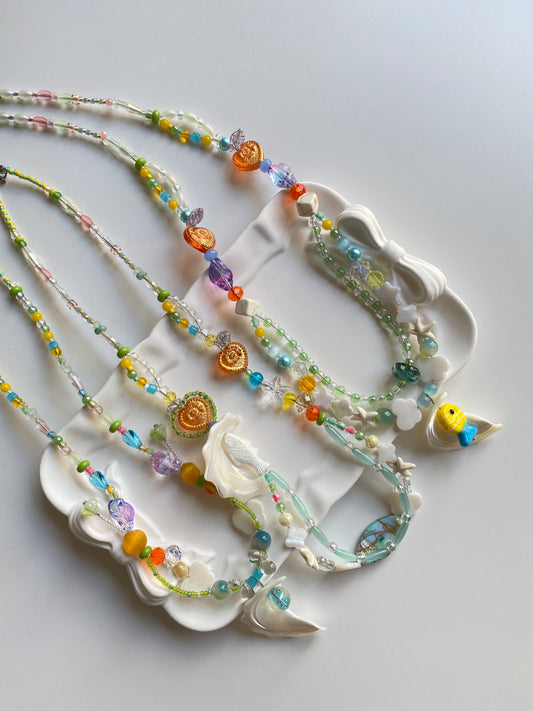 Close-up of colorful shell and fish themed handmade necklaces.