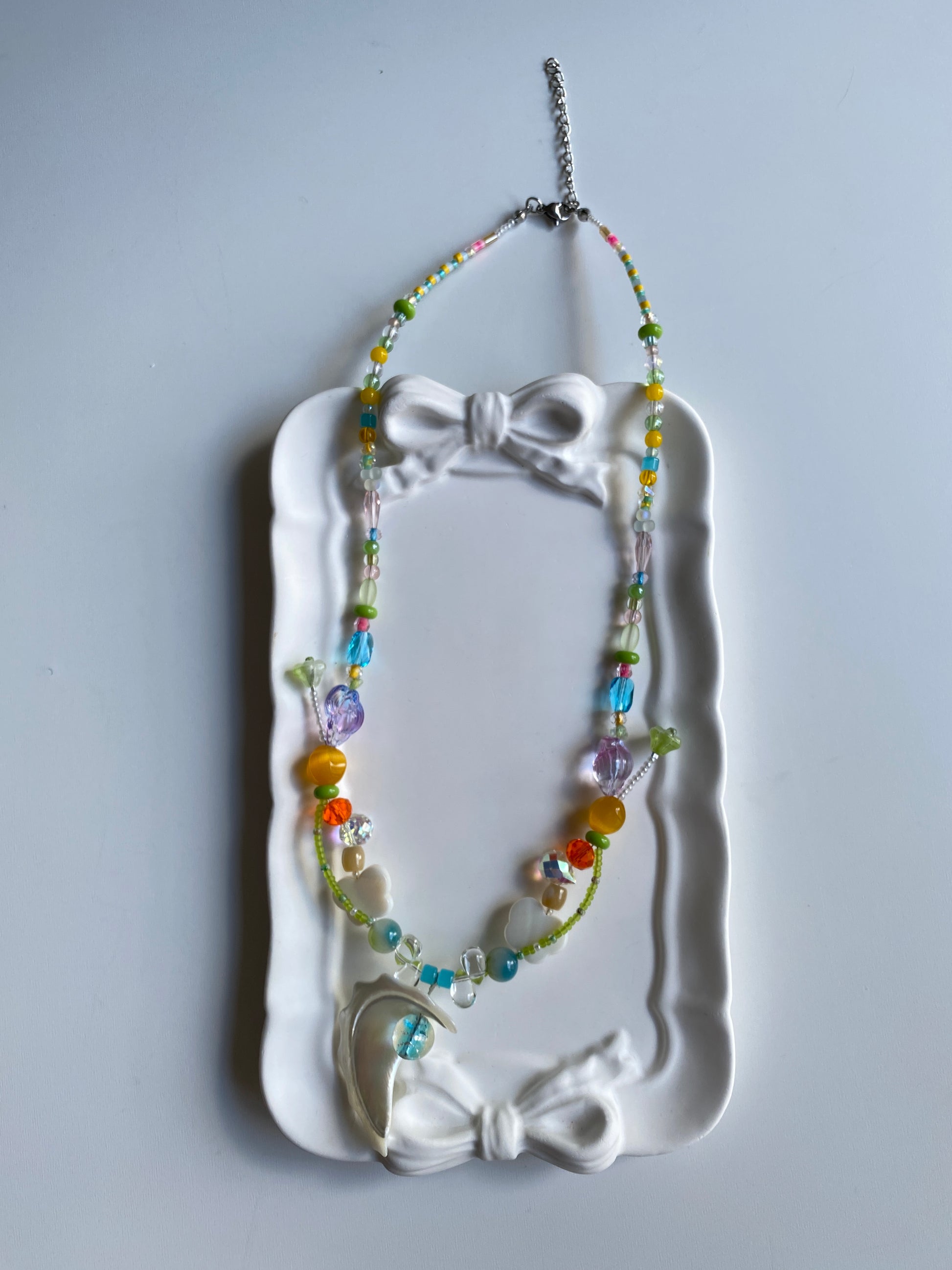 Shell pearl ocean necklace displayed on mannequin in natural light.