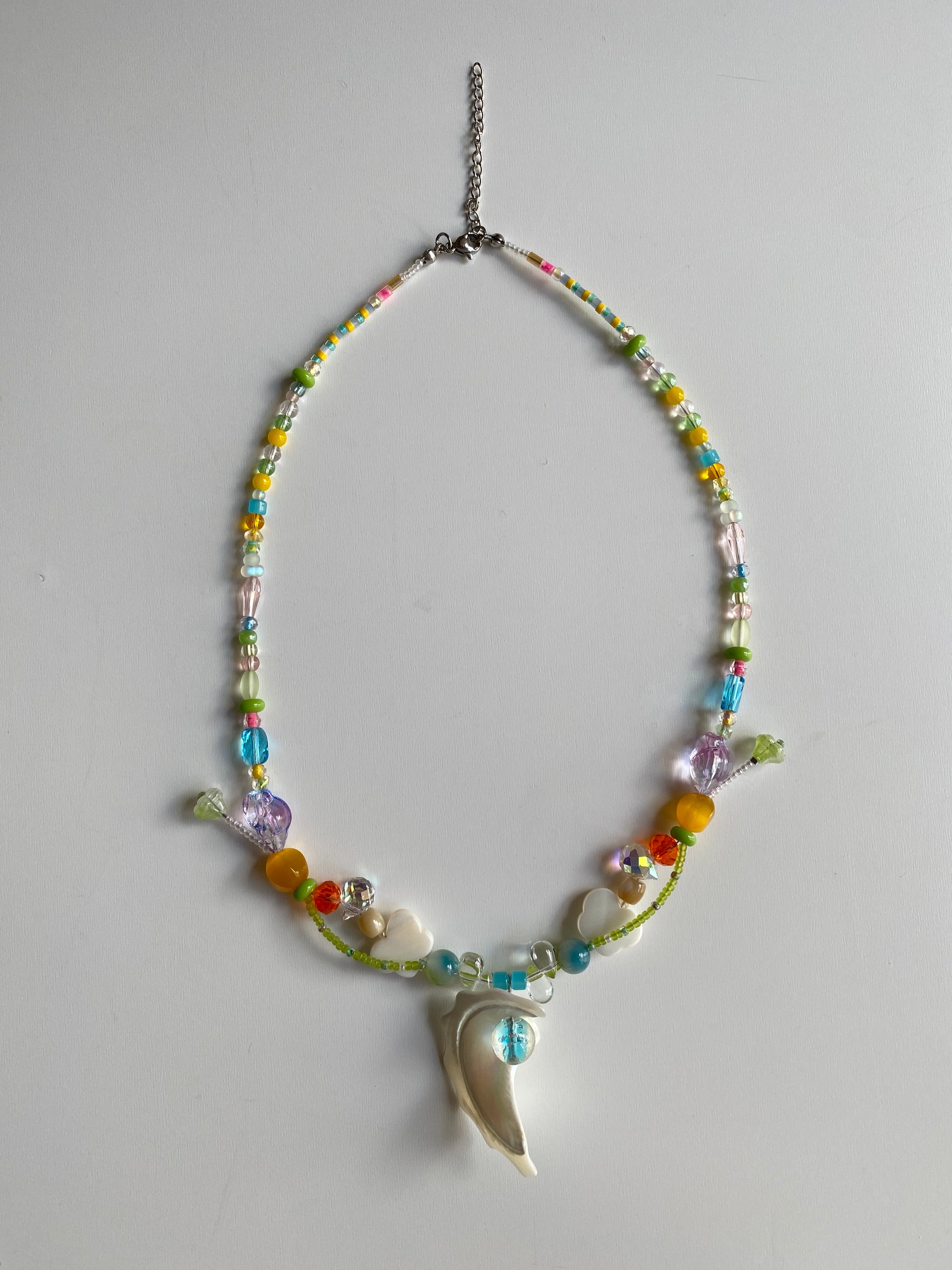 Detailed view of shell, butterfly shell charm and colorful beads.