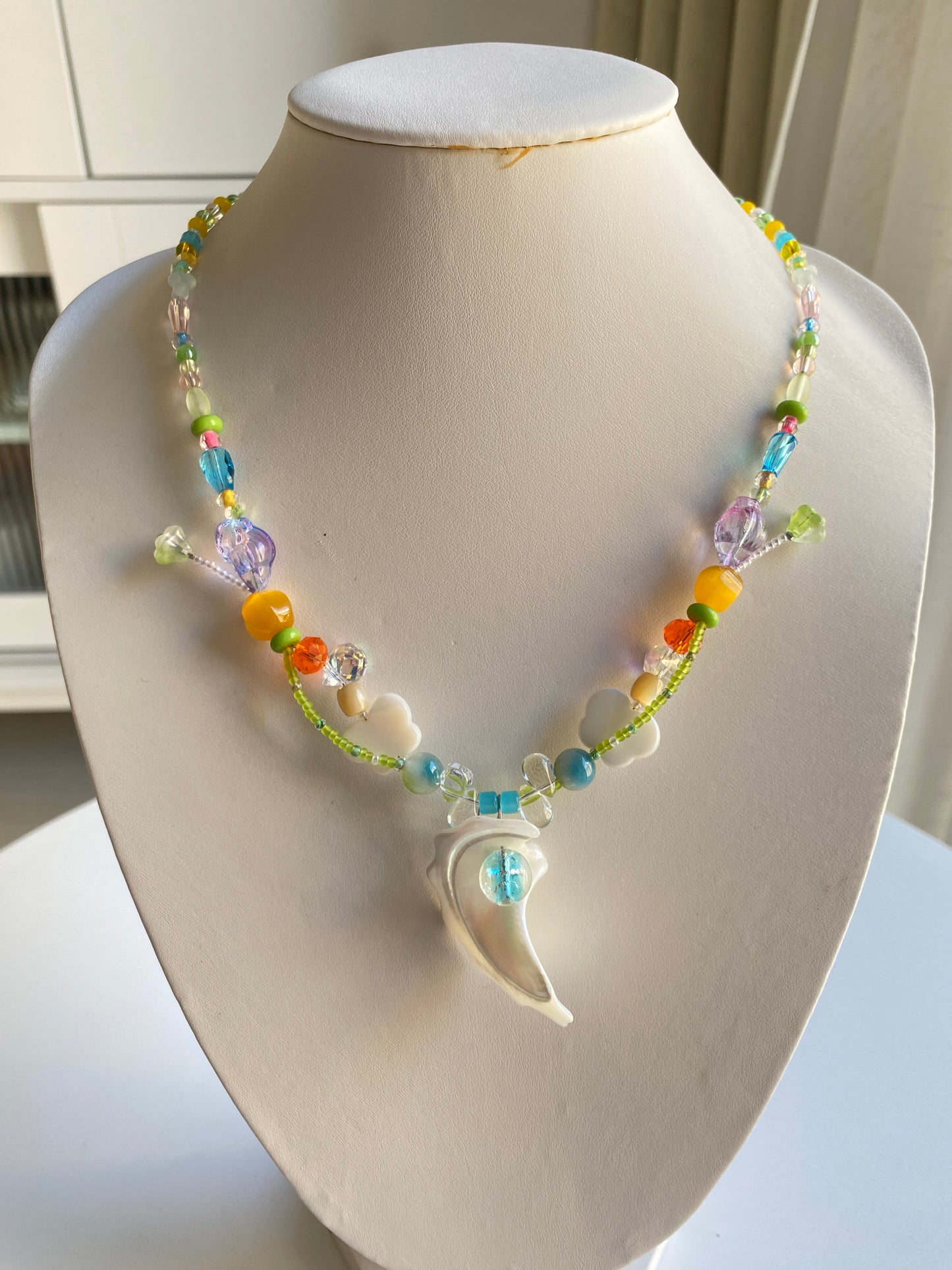 Handmade necklace with shell pendant and blue-centered pearl glass bead.