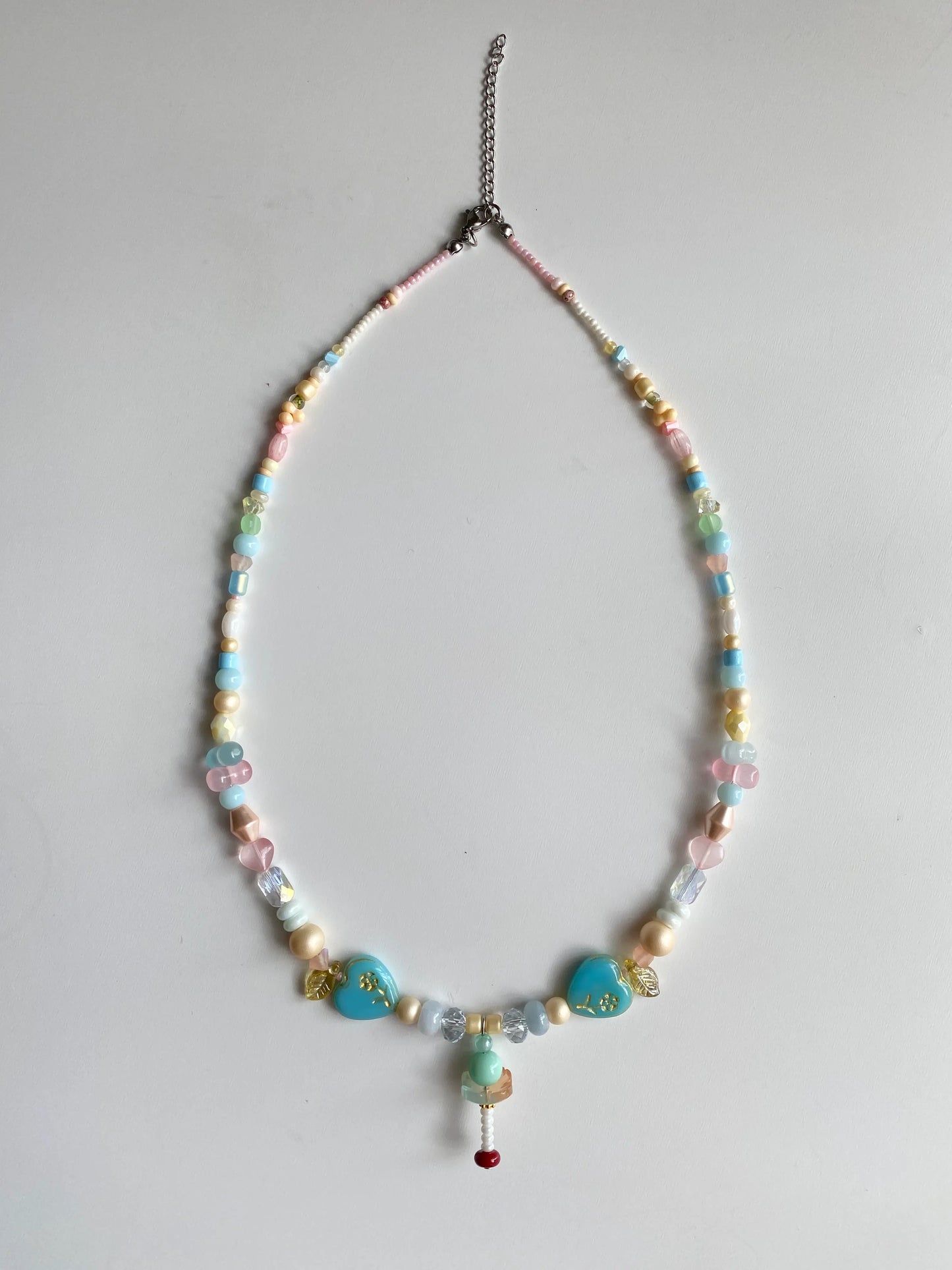 Flatlay of a playful glass beaded necklace with giant peanut and abacus shaped beads on a white surface.
