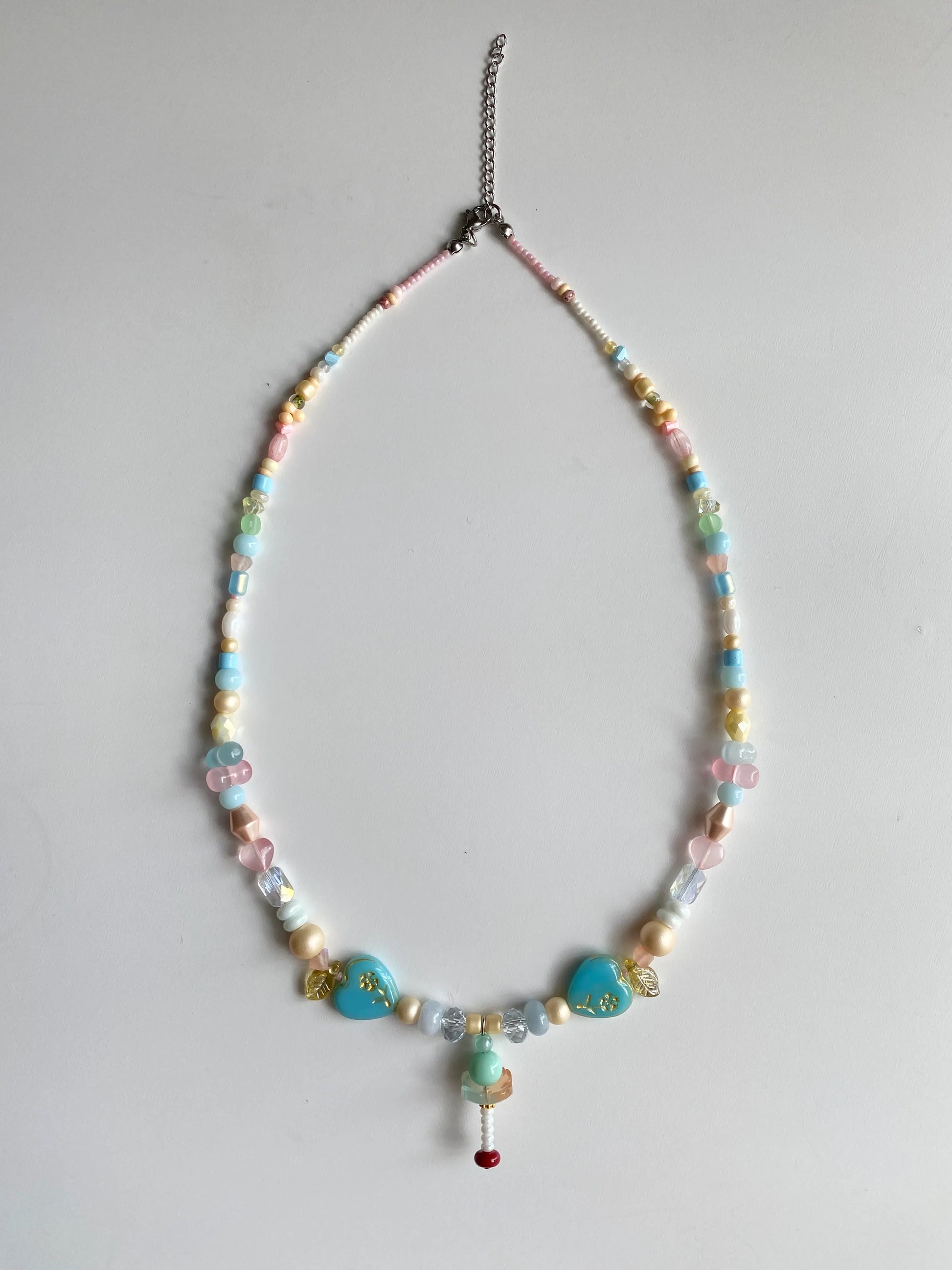 Flatlay of a playful glass beaded necklace with giant peanut and abacus shaped beads on a white surface.