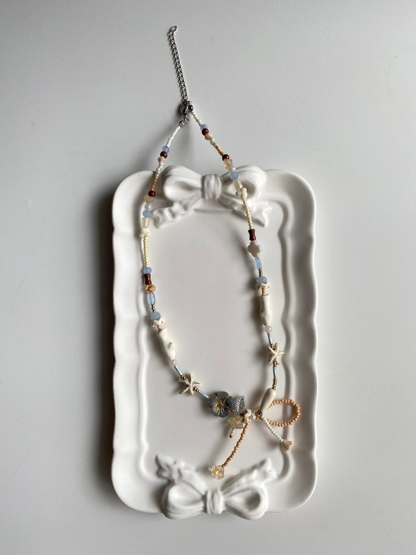 HuibenCraft 1-of-1 sweet and elegant summer necklace with light blue and sandy beige beads in a white ceramic dish, perfect for beach holidays.