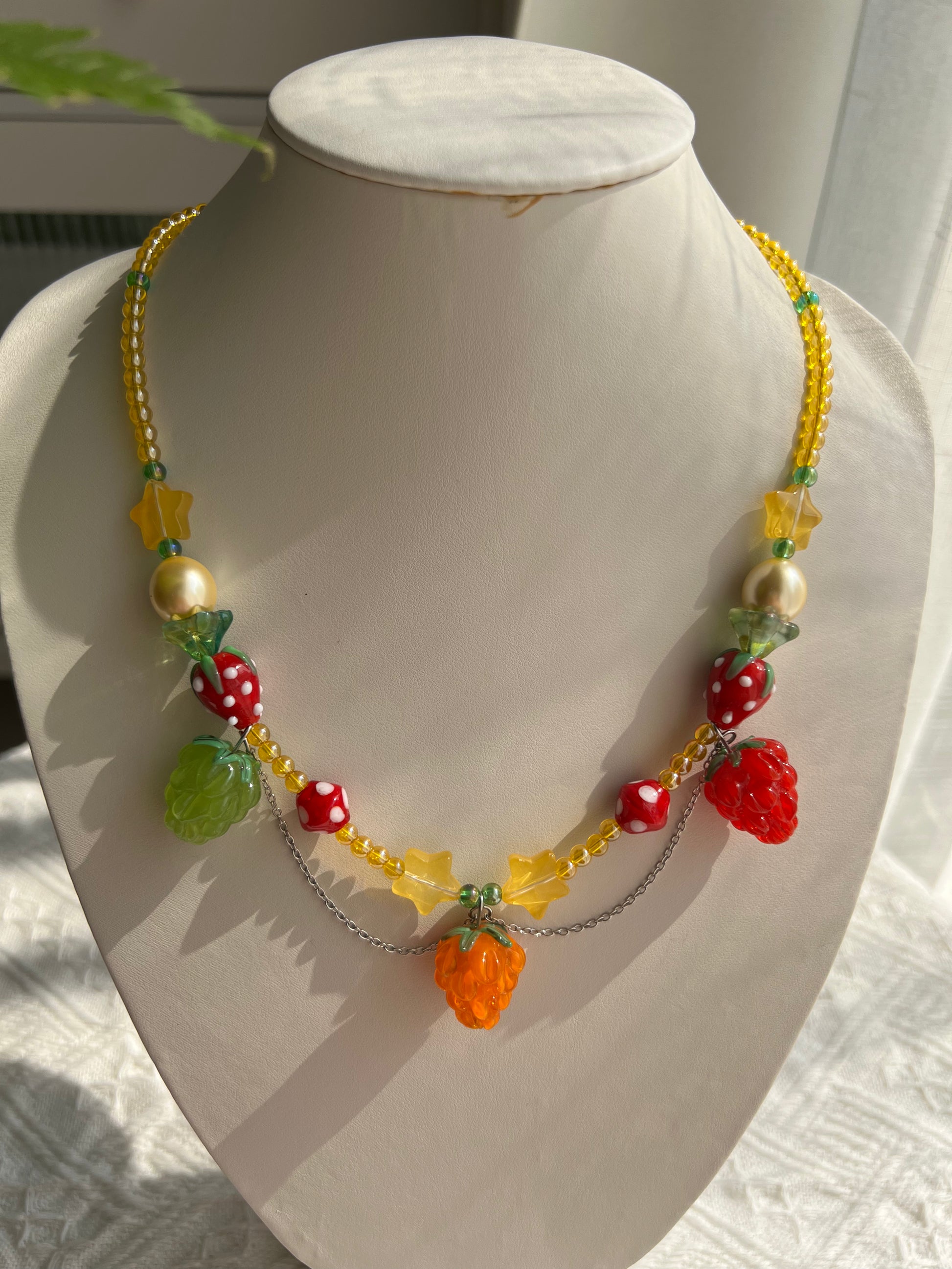 Sweet Raspberry Strawberry Necklace displayed on a necklace bust with colorful glass beads.