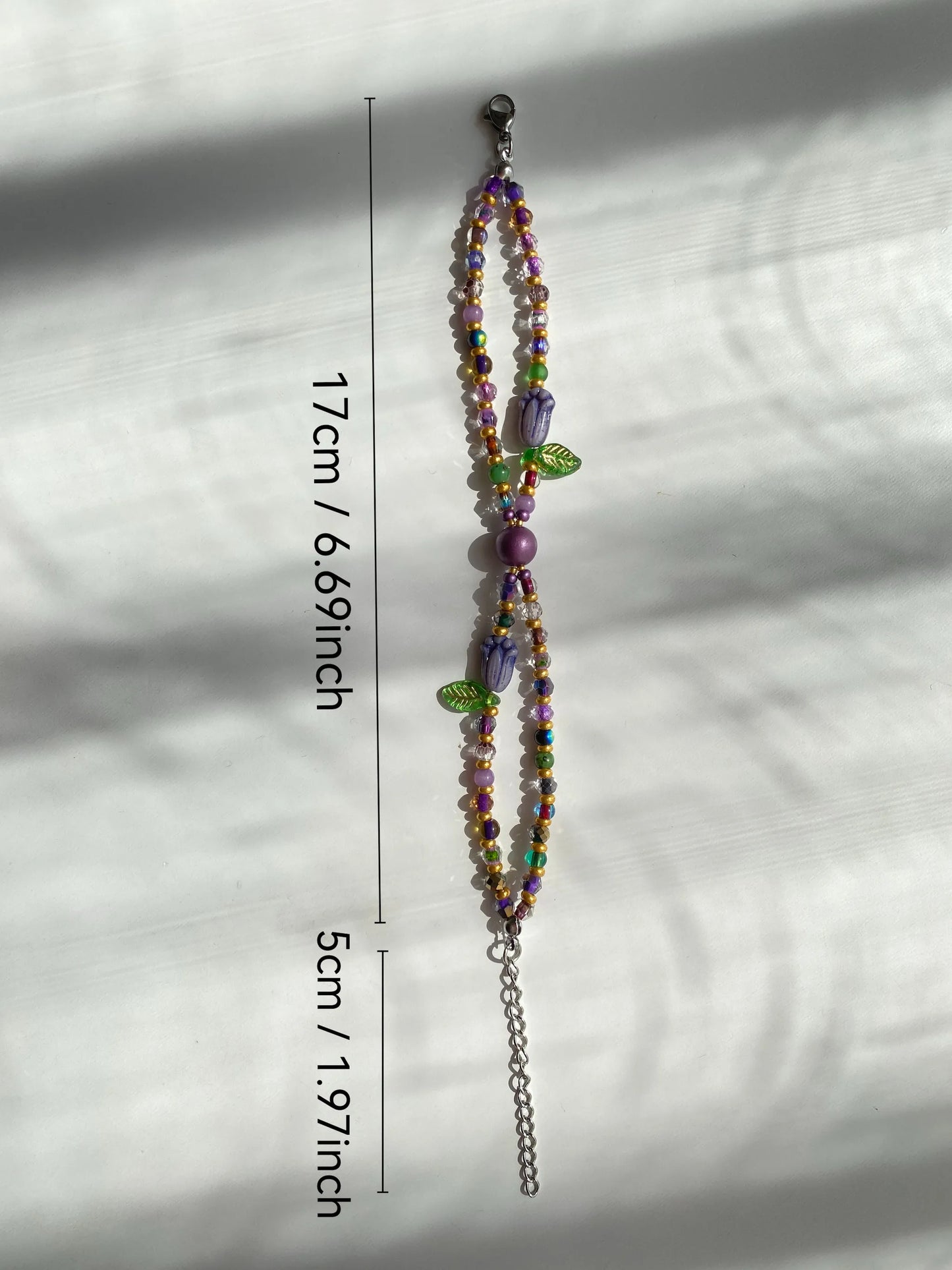 Unique 1-of-1 purple tulip glass bead bracelet with gold accents, double-layered style on a sunlit white desk.