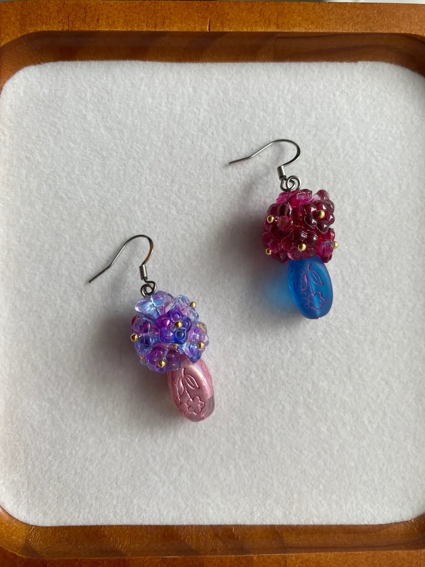 HuibenCraft 1-of-1 unique artisan Czech glass vase earrings filled with diverse blue and purple flowers in a white dish.