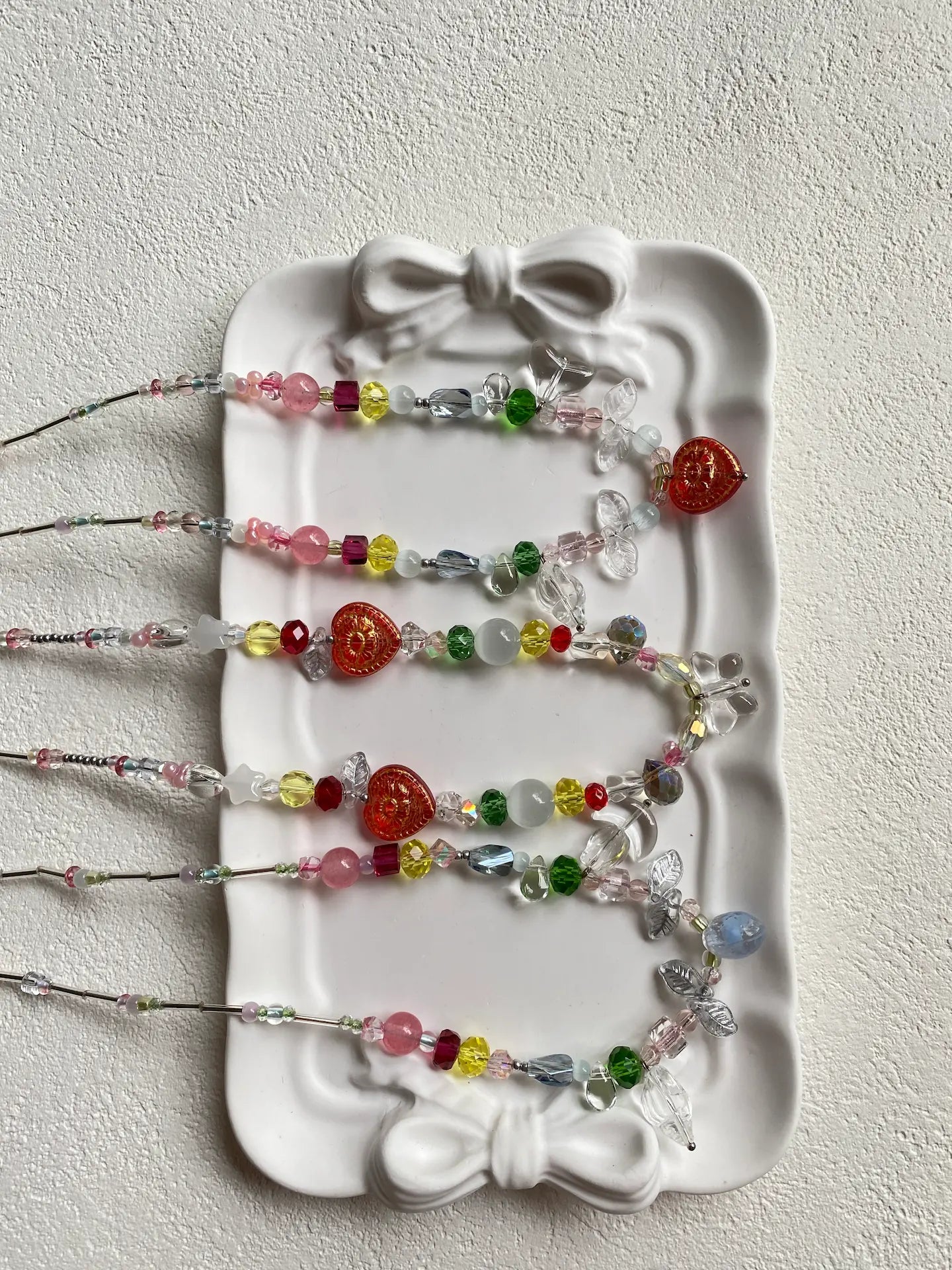 HuibenCraft trio of 1-of-1 vibrant colorful seed bead necklaces arranged as a flat lay in a plate, top-down view highlighting a bright, beach-ready aesthetic.