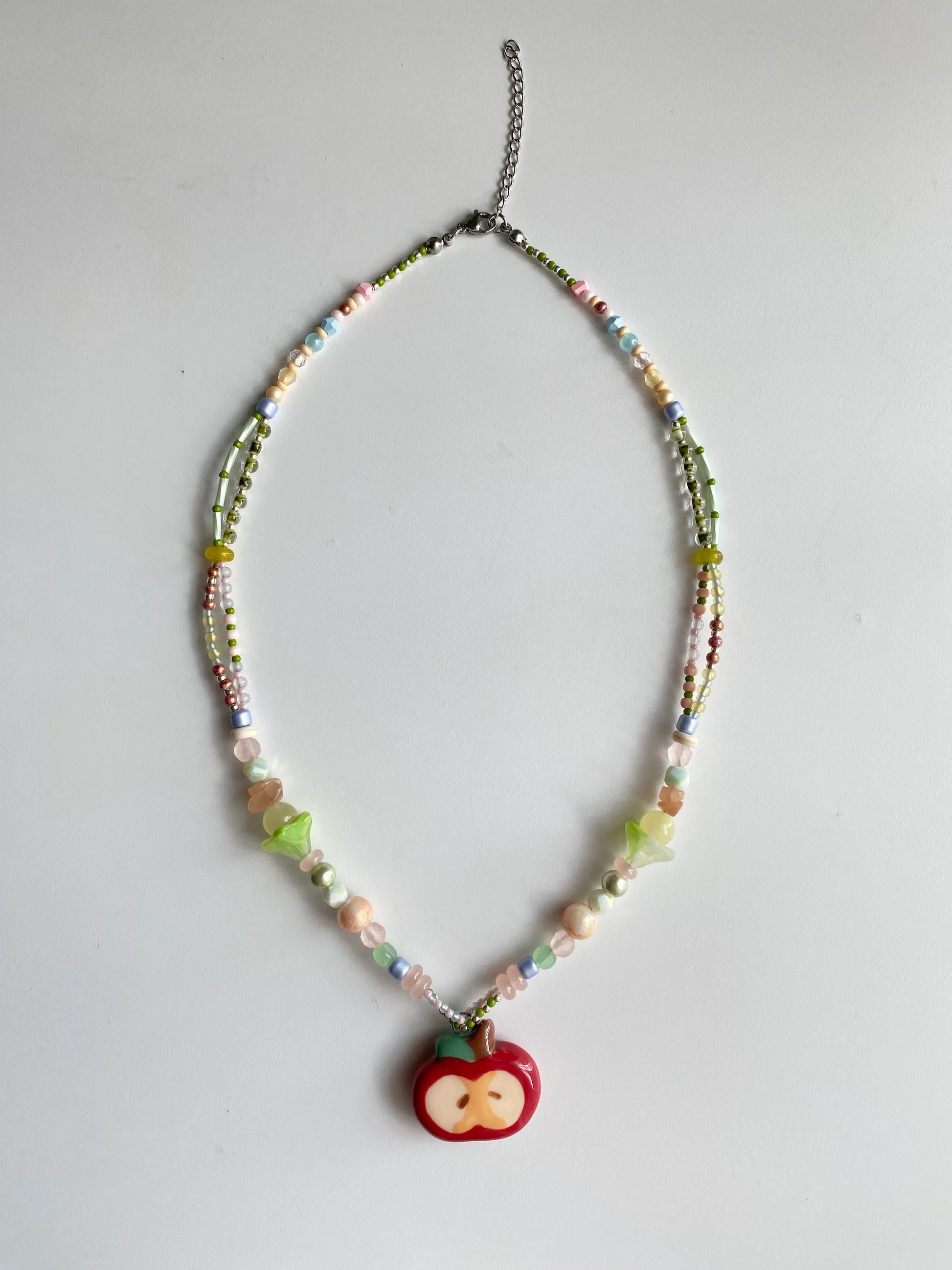 Flatlay of a 1-of-1 handmade necklace featuring Czech glass flowers and pastel beads on a white table.