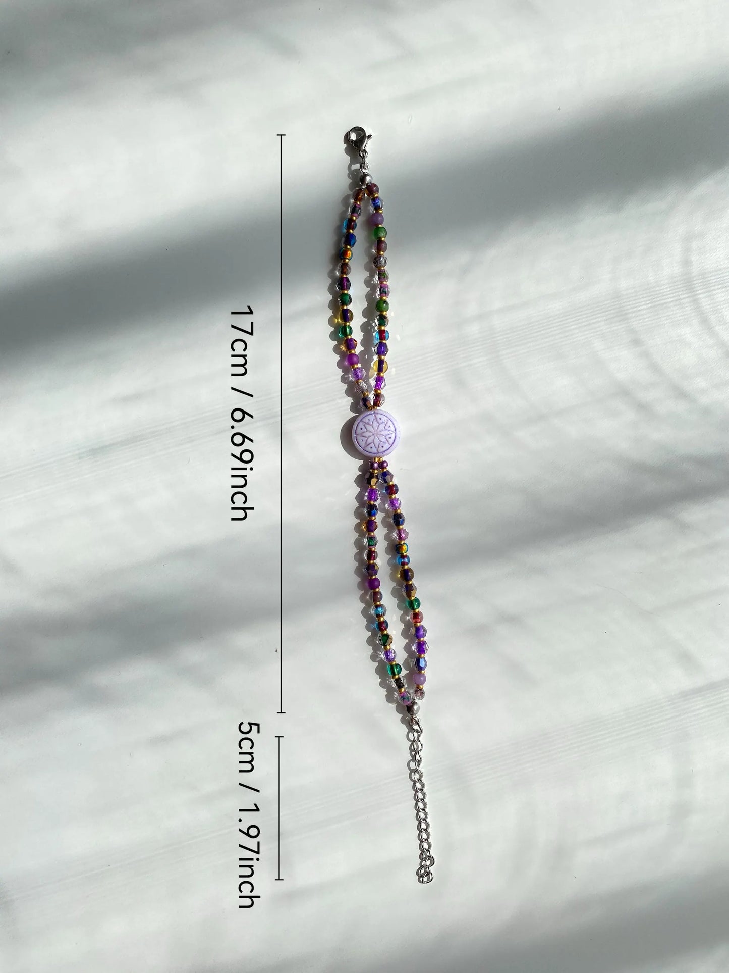 A 1-of-1 white and purple edged Octagram beaded bracelet, double-layered design on a white surface with natural sunlight.